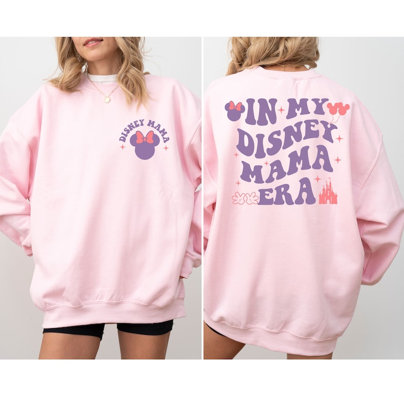 May include: Pink sweatshirt with a purple graphic of Mickey Mouse on the front and the text "In My Disney Mama Era" with a purple castle and Mickey Mouse hands on the back.