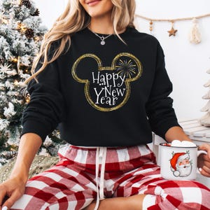 May include: Black sweatshirt with a gold glitter Mickey Mouse head design and the text "Happy New Year". The person is wearing red and white plaid pajama pants.