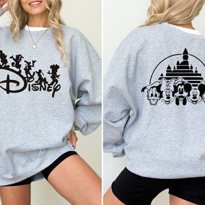 Puede incluir: Sudadera gris con un logotipo de Disney negro y personajes en la parte delantera y una silueta negra del castillo de Disney y personajes en la parte posterior.