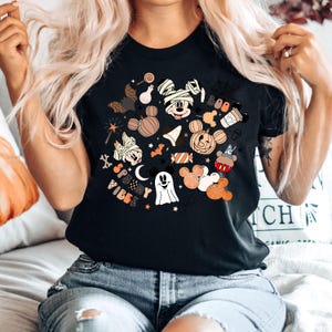 May include: Black t-shirt with a Halloween-themed design featuring Mickey Mouse and friends. The design includes pumpkins, bats, candy, and the text "Spooky Vibes".