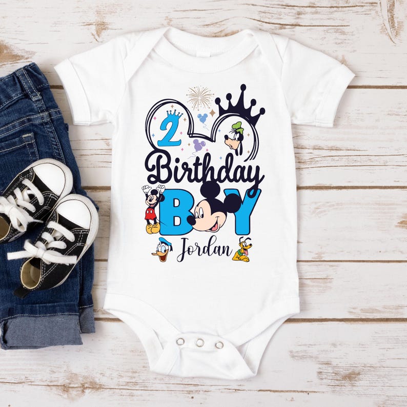 Op de afbeelding: Witte romper met een blauw Mickey Mouse-orenontwerp. Het ontwerp bevat Mickey Mouse, Donald Duck, Goofy en Pluto. De tekst op de romper luidt "2 Birthday Boy Jordan".