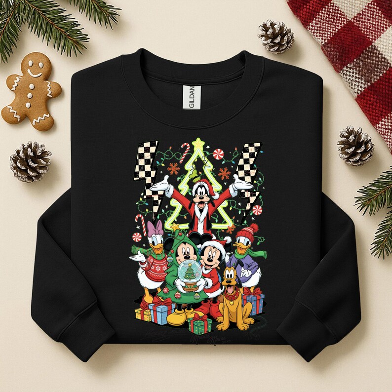 May include: Black sweatshirt featuring a festive graphic of Mickey Mouse and friends dressed for Christmas. The design includes a Christmas tree, presents, and candy canes. The characters are surrounded by decorative lights.