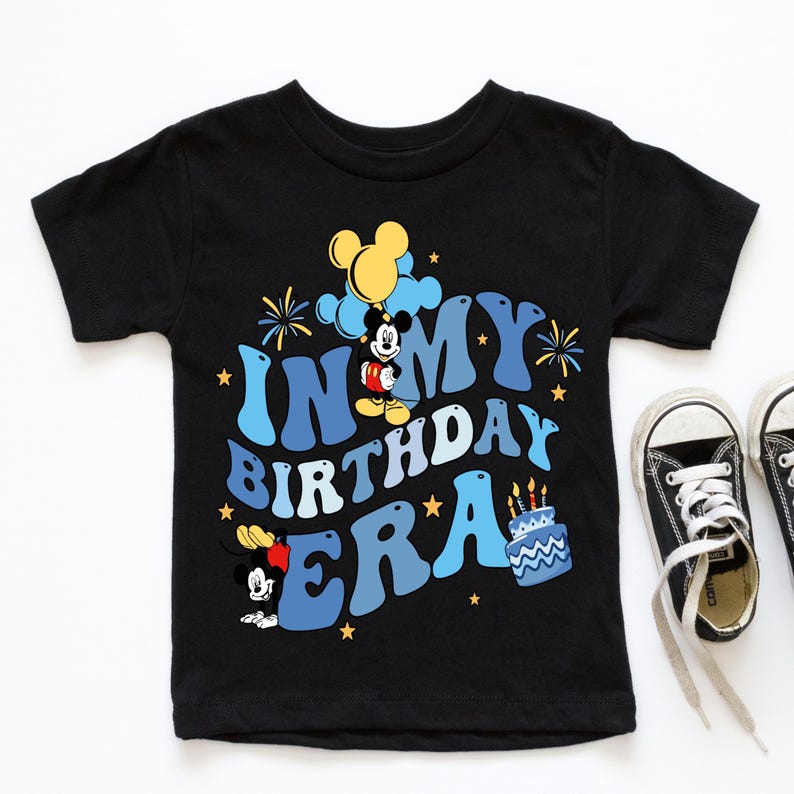 May include: Black t-shirt with a blue and yellow graphic of Mickey Mouse celebrating his birthday. The text on the shirt reads "In My Birthday Era".