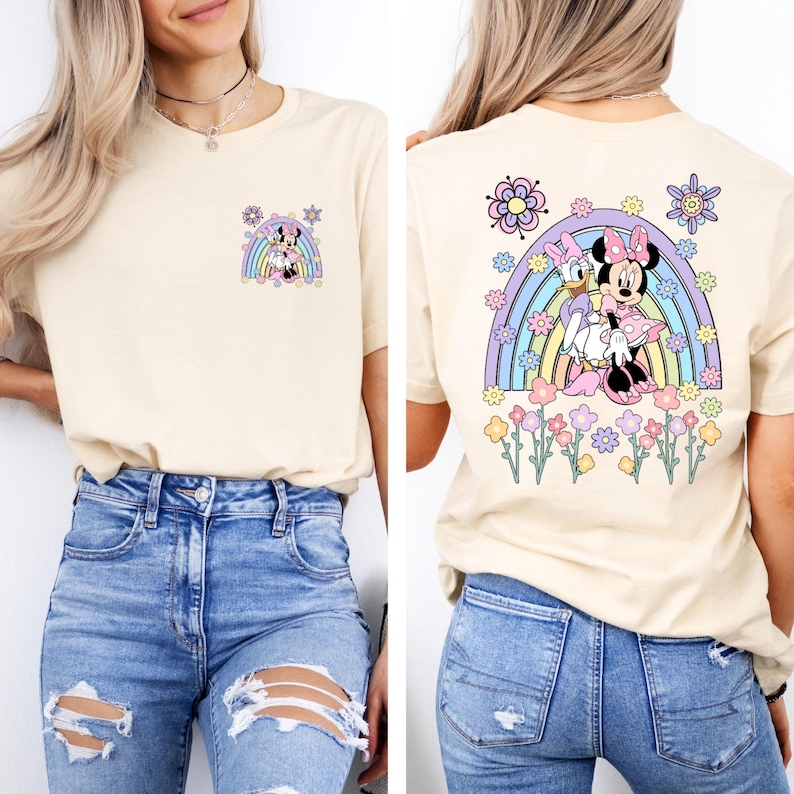May include: A light beige t-shirt with a rainbow and Minnie Mouse and Daisy Duck graphic on the back. The front of the shirt has a smaller version of the graphic on the left side of the chest.