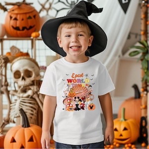 May include: A child wearing a black witch hat and a white t-shirt with the text "Epcot World Tour" and cartoon characters. The background includes Halloween decorations such as pumpkins and a skeleton.