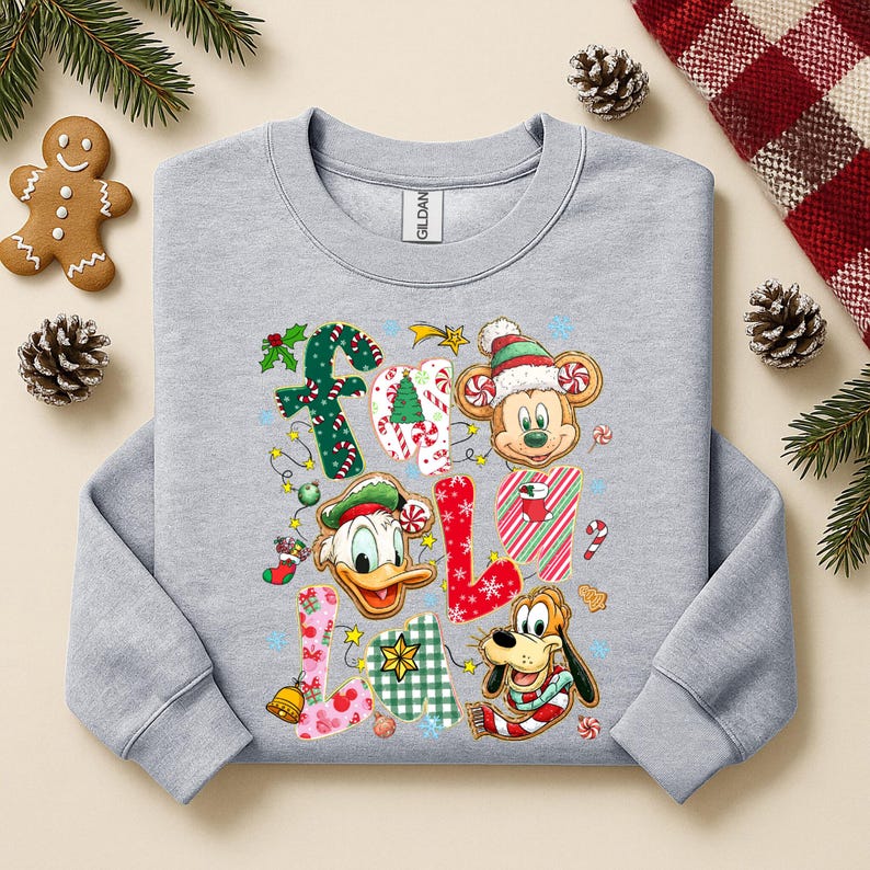 K&ouml;nnte beinhalten: Ein hellgraues Sweatshirt mit einem farbenfrohen "Fall Y'all"-Design mit Disney-Figuren und festlichen Elementen. Das Design umfasst Micky Maus, Donald Duck und Pluto sowie Zuckerstangen und Lichterketten.