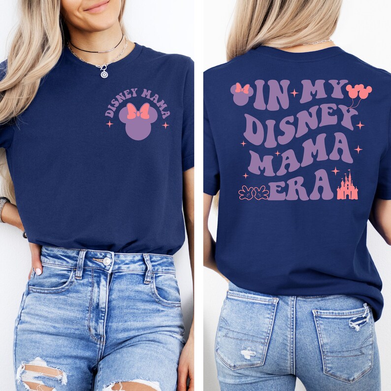 May include: A navy blue t-shirt with a pink and white Mickey Mouse silhouette on the front and the text "Disney Mama" in a retro font. The back of the shirt has the text "In My Disney Mama Era" in a retro font with pink Mickey Mouse ears and a pink castle graphic.