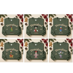 May include: Six olive green sweatshirts with the Disneyland logo and various Disney character designs. Each sweatshirt has the text "Disneyland est 1955 California". The characters include Mickey Mouse, Minnie Mouse, Donald Duck, Daisy Duck, Goofy, and a character in a Christmas outfit.