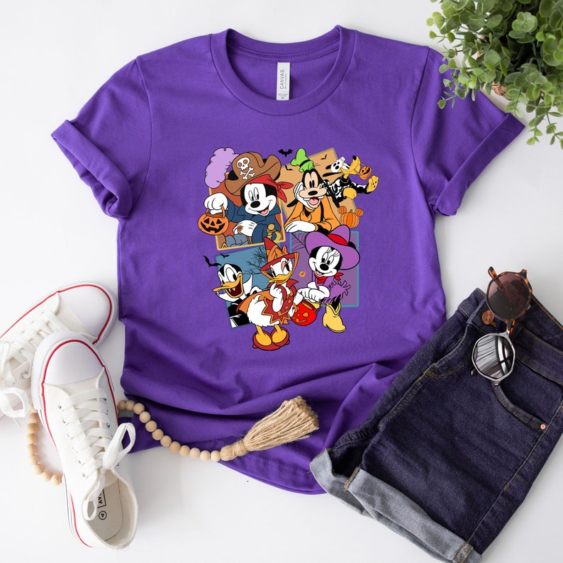 May include: Purple t-shirt with a graphic print of Mickey Mouse, Minnie Mouse, Donald Duck, Goofy, and Pluto dressed in Halloween costumes. The characters are holding pumpkins and candy.