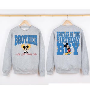 Puede incluir: Sudadera gris con un gr&aacute;fico de Mickey Mouse azul y rojo y el texto "Brother of the Birthday Boy" en la espalda. La parte delantera de la sudadera tiene el texto "Brother" en azul con un gr&aacute;fico de Mickey Mouse m&aacute;s peque&ntilde;o y el texto "Of The Birthday Boy" debajo.