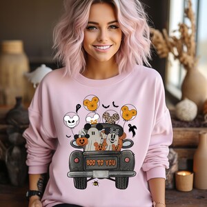 Peut inclure: Sweat-shirt rose avec un imprim&eacute; de Mickey Mouse et ses amis dans un camion noir avec le texte "Boo to You". Le camion est d&eacute;cor&eacute; de citrouilles et d'oreilles de Mickey Mouse.