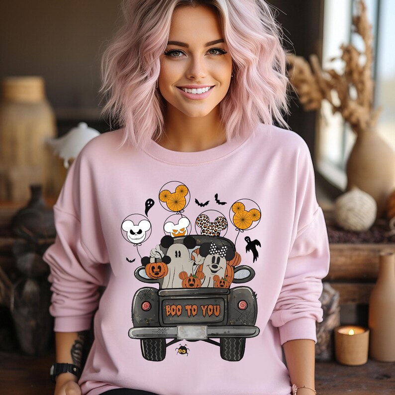 Peut inclure: Sweat-shirt rose avec un imprim&eacute; de Mickey Mouse et ses amis dans un camion noir avec le texte "Boo to You". Le camion est d&eacute;cor&eacute; de citrouilles et d'oreilles de Mickey Mouse.