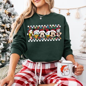 May include: Green Christmas sweater with a checkered pattern and a row of Disney characters wearing Santa hats. The characters include Mickey Mouse, Minnie Mouse, Donald Duck, Goofy, and Pluto.