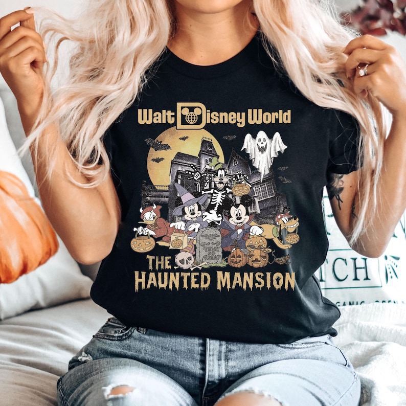 May include: Black t-shirt with a vintage-style graphic of Mickey Mouse and friends in front of the Haunted Mansion at Walt Disney World. The text "Walt Disney World" and "The Haunted Mansion" are printed on the shirt.