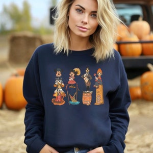 May include: A navy blue sweatshirt featuring a vintage-style graphic of Mickey Mouse and his friends. The graphic depicts Mickey Mouse, Minnie Mouse, Donald Duck, Goofy, and Pluto in a line, each with a unique pose and expression. The graphic is printed in a variety of colours, including red, yellow, orange, and green.