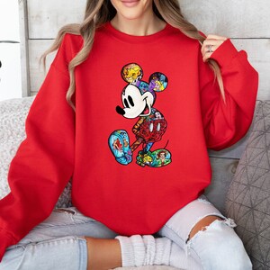 Puede incluir: Sudadera roja con un gr&aacute;fico de Mickey Mouse colorido. El gr&aacute;fico est&aacute; formado por diferentes personajes de Disney.