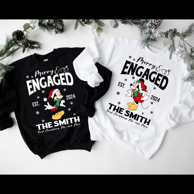 Puede incluir: Dos su&eacute;teres navide&ntilde;os negros y blancos con un dise&ntilde;o de Mickey Mouse. Los su&eacute;teres dicen "Merry & Engaged" con el a&ntilde;o 2024 y "The Smith" con el texto "First Christmas Mr. and Mrs."