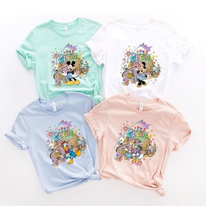 May include: Four t-shirts with different Disney characters and the word "Epcot" printed on them. The shirts are in different colors: light blue, light pink, white, and light green.