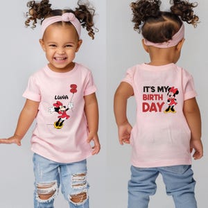 Puede incluir: Camiseta rosa con un gr&aacute;fico de Minnie Mouse y el texto "It's My Birthday" en la parte posterior. La parte delantera de la camiseta tiene un gr&aacute;fico de Minnie Mouse sosteniendo un globo con el texto "Luna" debajo.