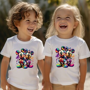 May include: Two children wearing white t-shirts with a colorful graphic print of Mickey Mouse and Minnie Mouse. The graphic features the characters with paint splatters around them.