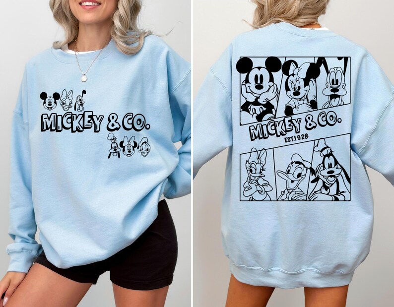 May include: Light blue sweatshirt with a black Mickey Mouse and friends graphic. The graphic includes Mickey Mouse, Minnie Mouse, Donald Duck, Goofy, and Pluto. The text "Mickey & Co. EST 1928" is printed below the graphic.