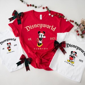 May include: A set of three white t-shirts with a red and black Mickey Mouse design. The shirts feature the text "Disneyworld est. 1971 Florida".
