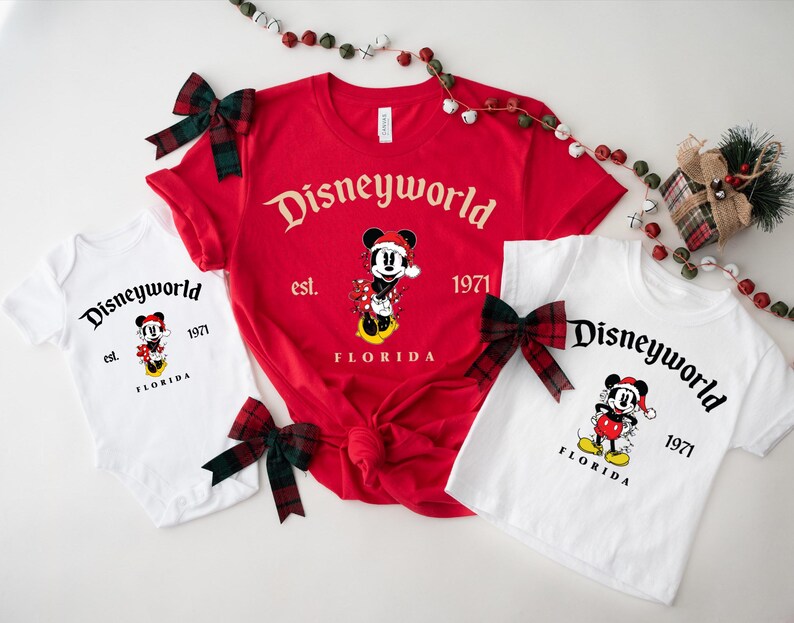 May include: A set of three white t-shirts with a red and black Mickey Mouse design. The shirts feature the text "Disneyworld est. 1971 Florida".