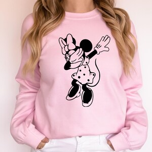 May include: A pink sweatshirt with a black graphic of a cartoon mouse doing the dab. The mouse is wearing a polka dot dress and a bow.