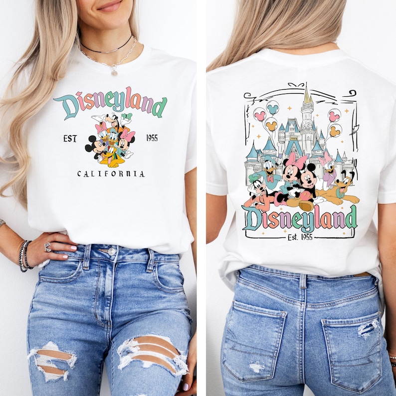 May include: A white t-shirt with a colorful Disneyland graphic on the front and back. The front graphic says 'Disneyland' with 'EST 1955' and 'CALIFORNIA' underneath. The back graphic features a colorful illustration of the Disneyland castle with Mickey Mouse, Minnie Mouse, Donald Duck, Goofy, and Pluto in front of it. The text on the back says 'Disneyland - Est. 1955'.