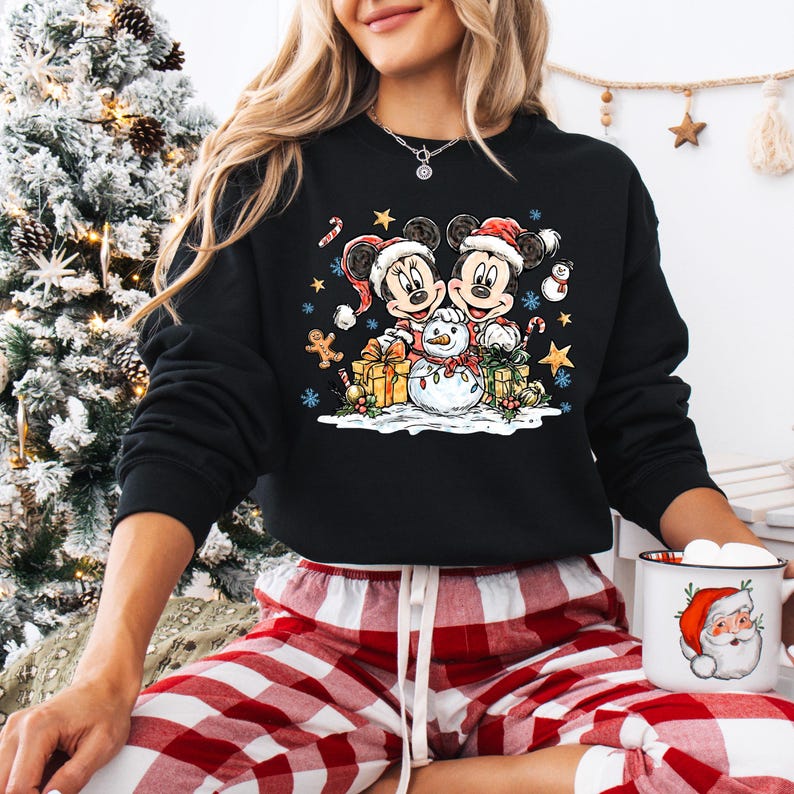 May include: Black sweatshirt featuring Mickey and Minnie Mouse in Santa hats, with a snowman, gifts, and Christmas decorations. The design includes candy canes, stars, and gingerbread men, perfect for holiday wear.