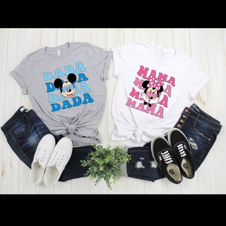 May include: Two gray and white t-shirts with a retro design featuring Mickey Mouse and Minnie Mouse wearing sunglasses. The shirts say "Dada" and "Mama" in a stacked design.