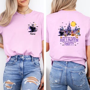 May include: A light pink t-shirt featuring a front and back design. The front displays a cartoon of a character with the text "Name". The back features a Halloween-themed design with the text "Mickey's Not So Scary Halloween Party".