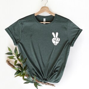 May include: A dark green t-shirt with a white peace sign graphic on the left chest.