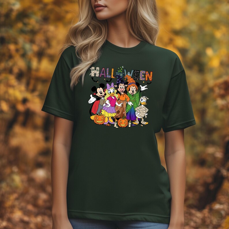 May include: Dark green t-shirt featuring a Halloween design with cartoon characters. The word "HALLOWEEN" is displayed in colorful letters above the characters. The characters include Mickey Mouse, Minnie Mouse, Donald Duck, and Goofy.