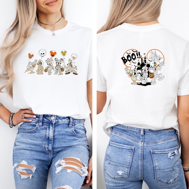 K&ouml;nnte beinhalten: Wei&szlig;es T-Shirt mit einem Halloween-Motiv auf der Vorder- und R&uuml;ckseite. Auf der Vorderseite sind Cartoon-Figuren als Mumien mit Luftballons zu sehen. Auf der R&uuml;ckseite sind ein Spukhaus, Spinnweben und das Wort "BOO!!" abgebildet.