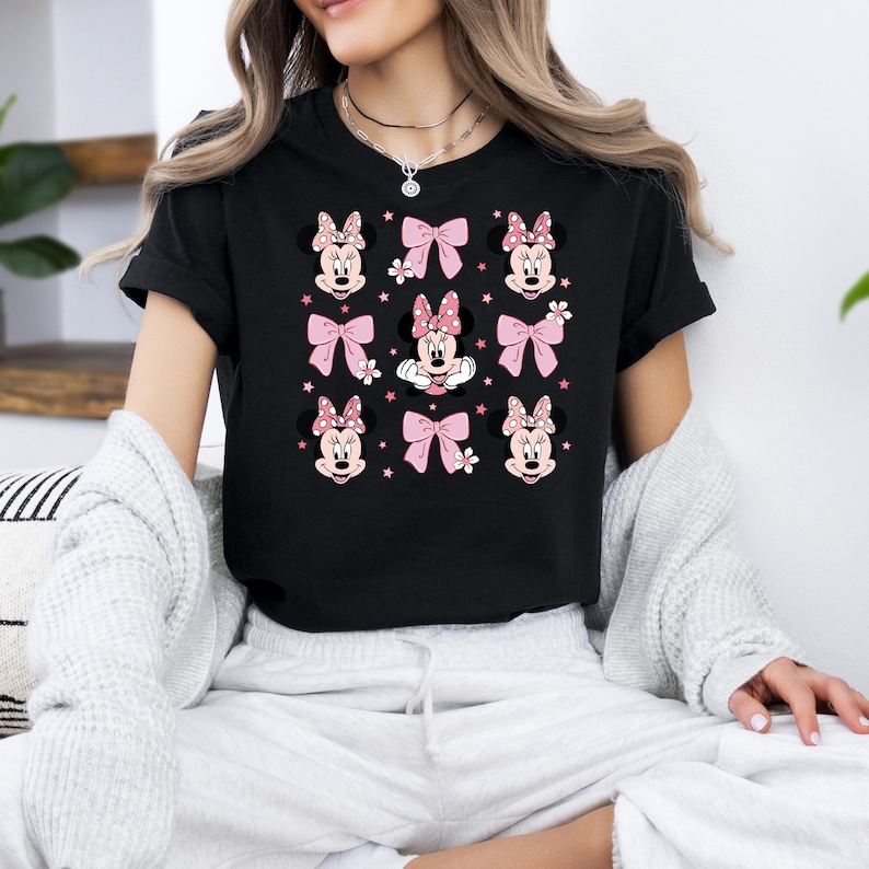May include: Black t-shirt with a repeated pattern of Minnie Mouse heads and pink bows.