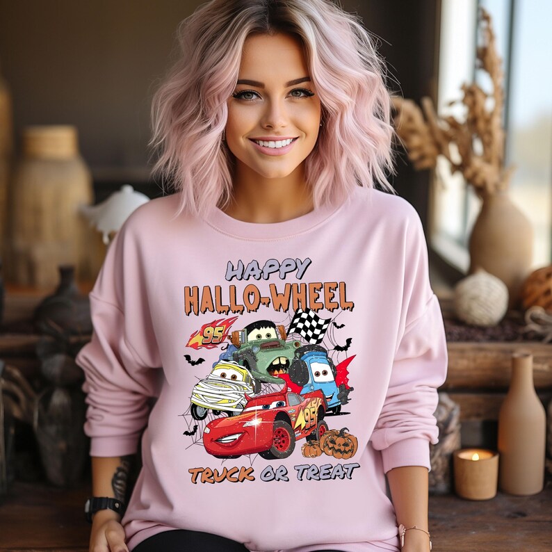 May include: Pink sweatshirt with a graphic of cartoon cars and the text "Happy Hallo-Wheel Truck or Treat".