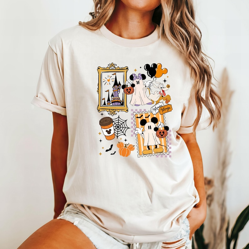 Puede incluir: Camiseta beige con un dise&ntilde;o tem&aacute;tico de Halloween. El dise&ntilde;o incluye im&aacute;genes enmarcadas de un castillo, Mickey Mouse como fantasma, una taza de caf&eacute; y calabazas. Tambi&eacute;n son visibles las palabras "Magic".