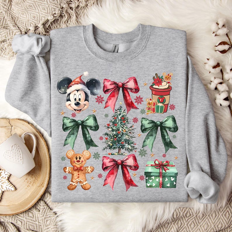 May include: A gray sweatshirt with a Christmas theme featuring Mickey Mouse, a Christmas tree, presents, bows, and gingerbread cookies.