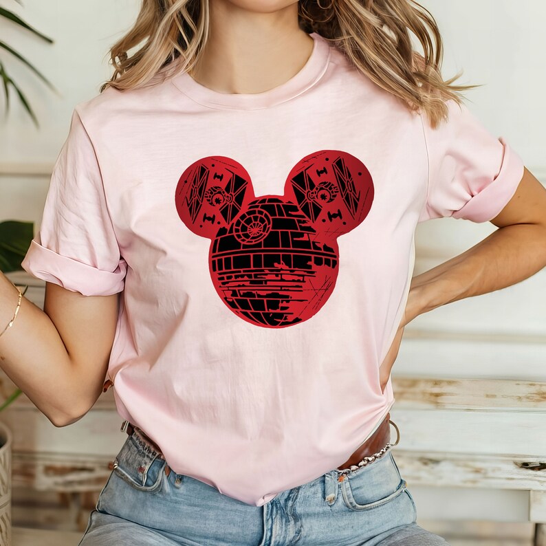 May include: A pink t-shirt with a red and black graphic of the Death Star from Star Wars designed in the shape of Mickey Mouse's head.