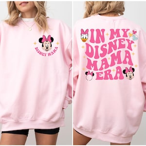 May include: Pink sweatshirt with a graphic of Minnie Mouse and the text "Disney Mama" on the front and the text "In My Disney Mama Era" on the back.
