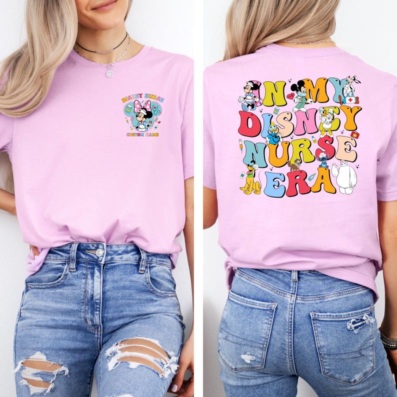May include: A light pink t-shirt with the text "Disney Rules" and a Minnie Mouse graphic on the front. The back of the shirt features the text "In My Disney Nurse Era" with various Disney character illustrations. The shirt is paired with blue jeans.