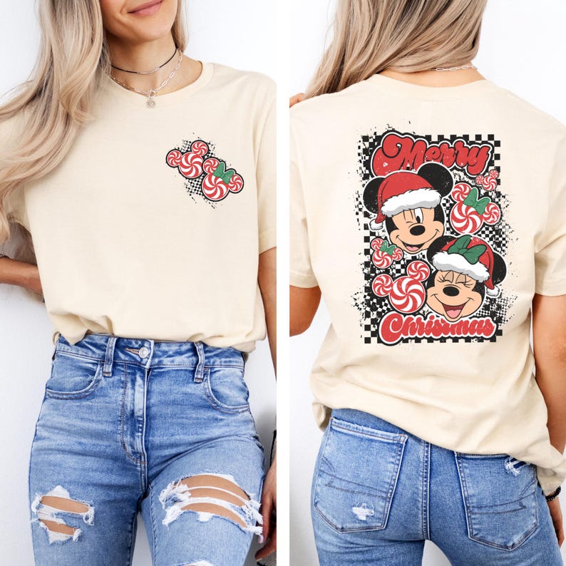 May include: Cream-colored t-shirt featuring a Christmas design. The front has a small candy cane graphic, while the back displays Mickey and Minnie Mouse in Santa hats with the words "Merry Christmas". The design includes red, white, and black elements.