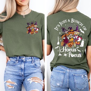 May include: A green t-shirt with a graphic of the Sanderson sisters from Hocus Pocus on the front and the text "It's just a bunch of Hocus Pocus" on the back.