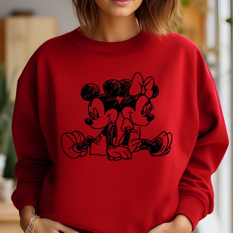 May include: Red sweatshirt with a black graphic of Mickey Mouse and Minnie Mouse holding hands.