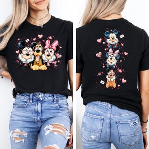 May include: Black t-shirt featuring Mickey Mouse, Goofy, and Minnie Mouse with pink hearts and the text "I Love You." The back of the shirt shows the characters again. A fun, romantic design.