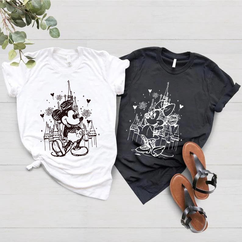 May include: Two t-shirts with a black and white sketch of Mickey Mouse and Minnie Mouse in front of Cinderella's Castle. The t-shirts are white and black.
