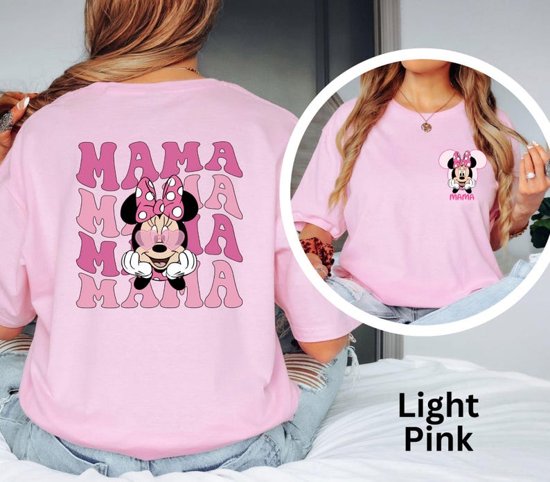 Puede incluir: Camiseta rosa claro con un dise&ntilde;o de Minnie Mouse y la palabra "MAMA" en una fuente retro. El dise&ntilde;o se repite en la parte posterior. La camiseta es de color rosa claro.