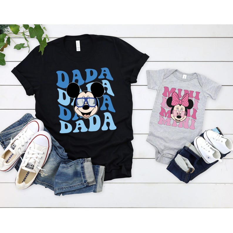 May include: A black t-shirt with a blue and white graphic of Mickey Mouse wearing sunglasses and the word "DADA" repeated. A grey bodysuit with a pink and white graphic of Minnie Mouse and the word "MIMI" repeated.