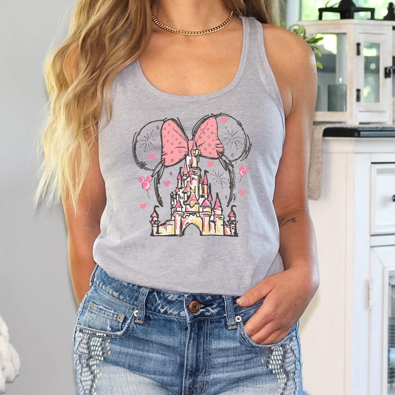 May include: A gray tank top with a pink bow and a sketch of Cinderella's castle. The castle is surrounded by fireworks and balloons.